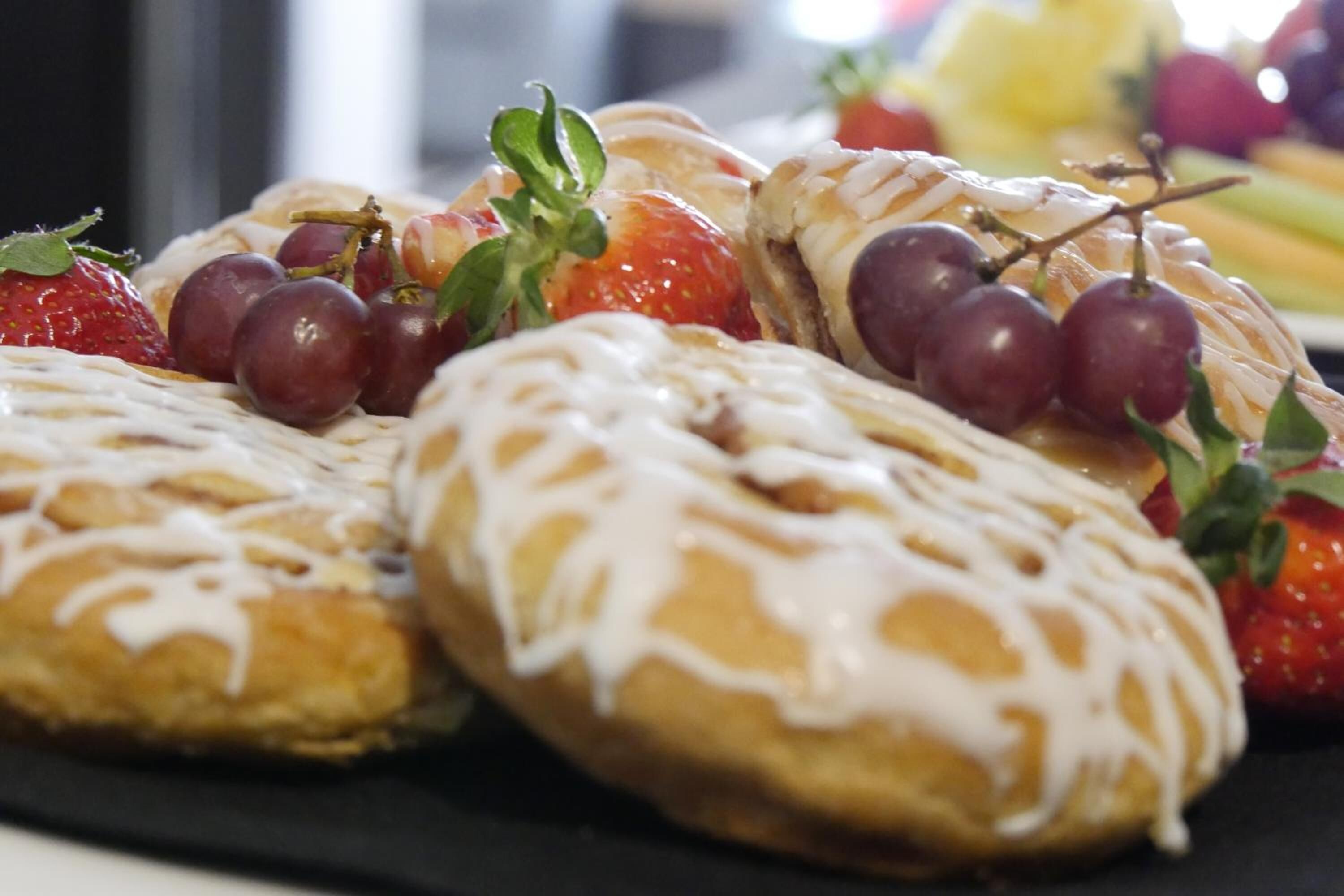 A plate of pastries with white icing and fresh fruit.