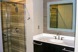 A modern bathroom with a glass shower enclosure, a vanity with a sink, and a mirror with a wooden frame. - River Bend Casino & Hotel (Wyandotte)