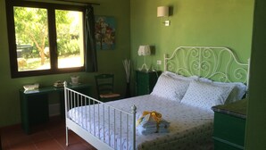 Un dormitorio con una cama, paredes verdes, una ventana, un escritorio y una silla.