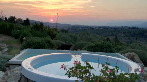 Un jacuzzi con vistas a la puesta de sol y el paisaje circundante.