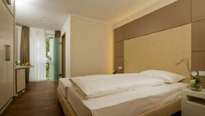 A hotel room with a large bed, a bedside table with a lamp, and a view of a corridor with a door leading outside. - Hotel & Restaurant Bakenhof (Münster)