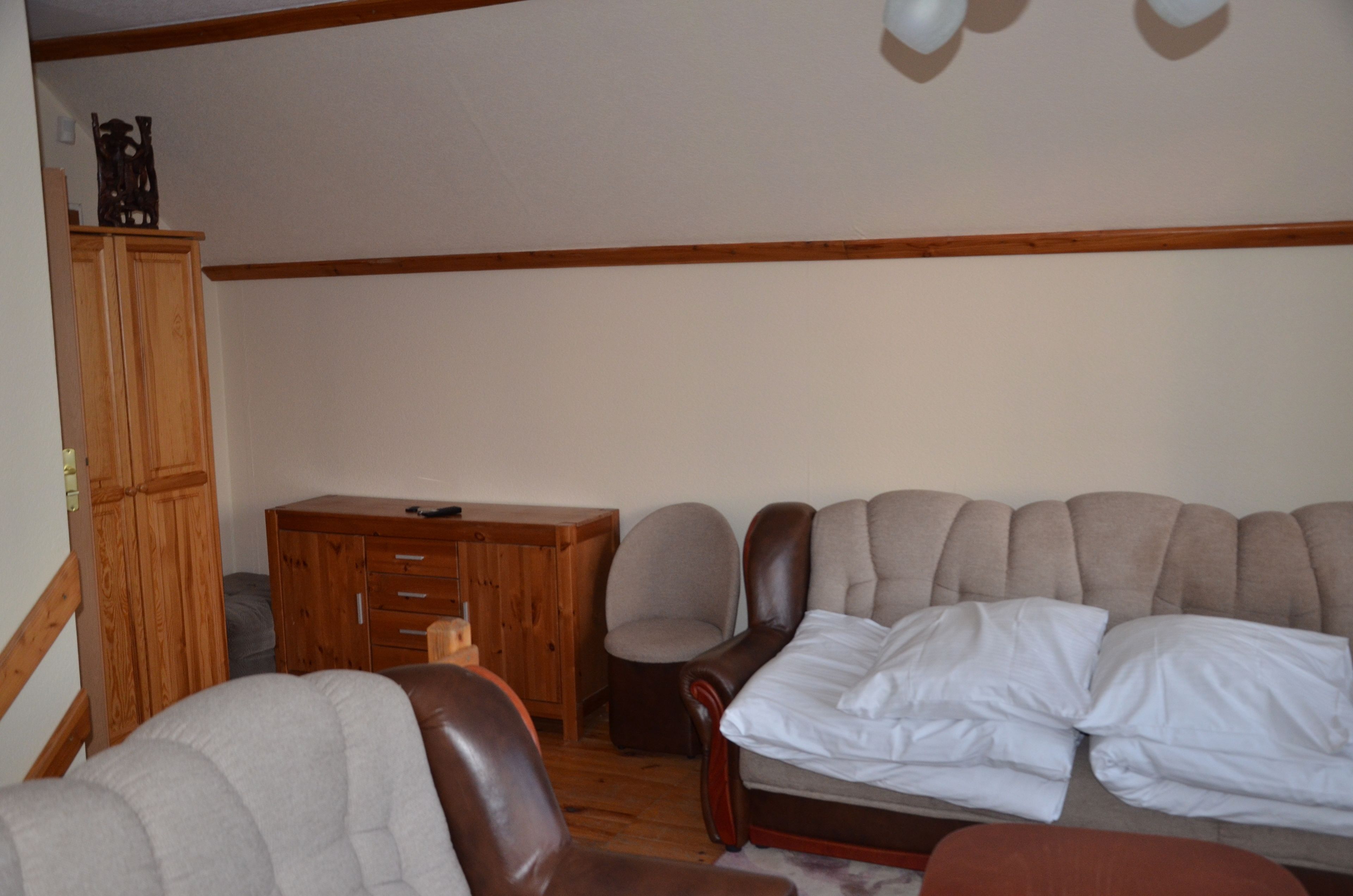 A living room with a sofa, a wooden cabinet, and a desk.