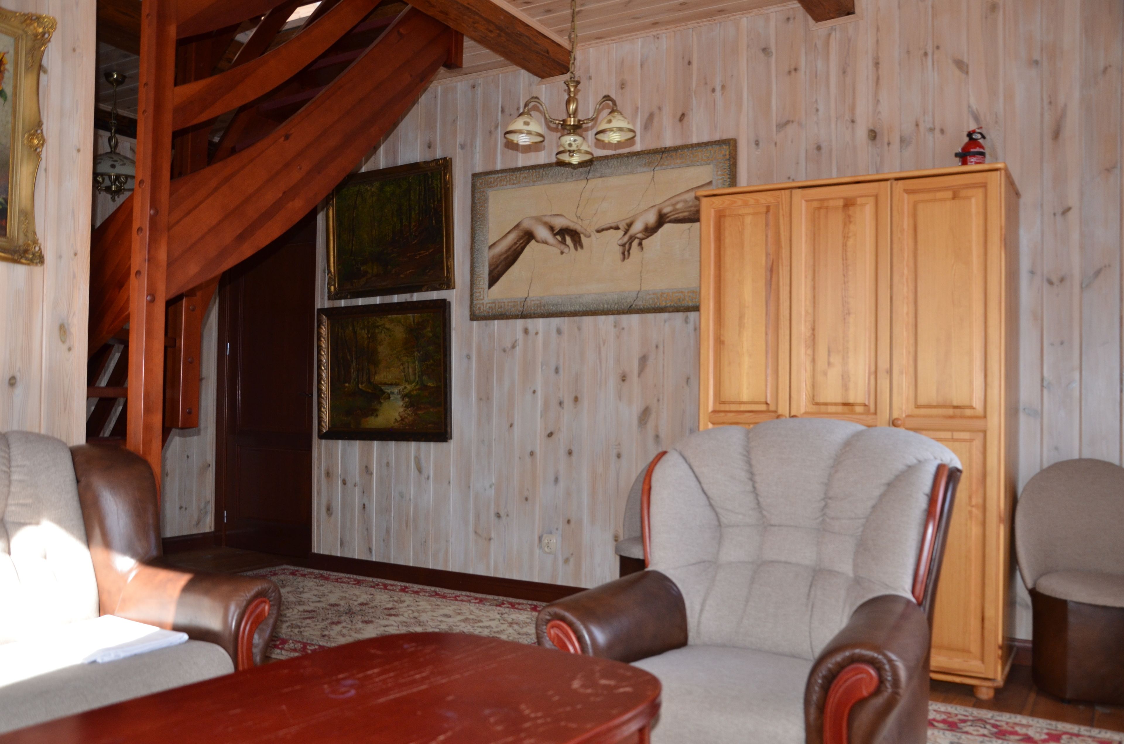 Een kamer met houten lambrisering, een kroonluchter, een grote kast en leren fauteuils.