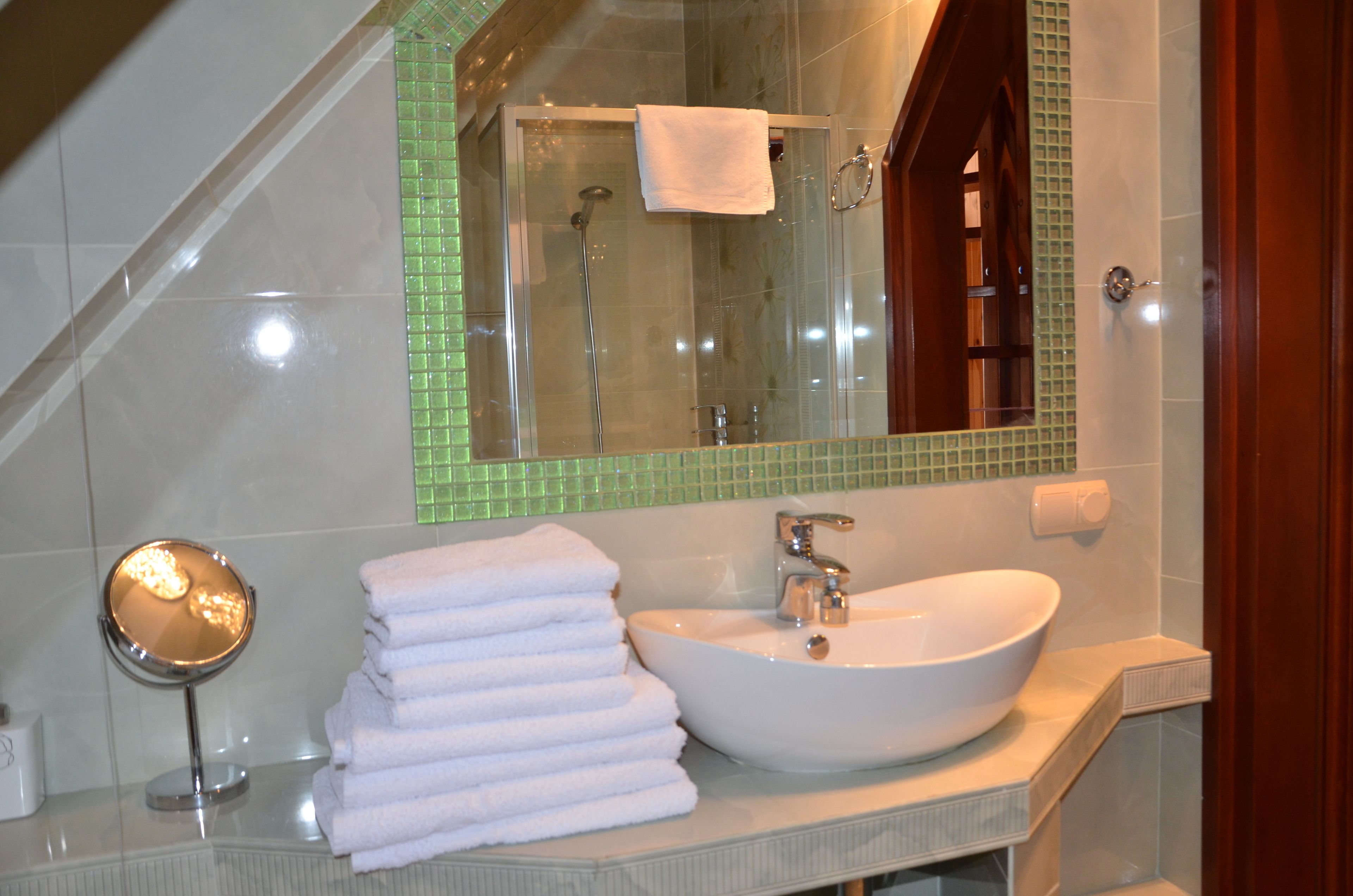 Un baño con ducha envuelta en vidrio, un lavabo blanco y un espejo.