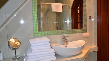 Un baño con ducha envuelta en vidrio, un lavabo blanco y un espejo.