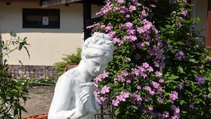 A white statue of a woman in a garden with a house in the background. - Dworek Mazurski Lizer (Pozezdrze)