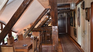 A rustic interior with a wooden dining table, chairs, and a staircase leading to an upper level. - Dworek Mazurski Lizer (Pozezdrze)