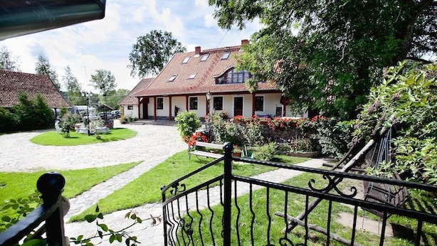 A courtyard with a house, a paved path, and a metal fence. - Dworek Mazurski Lizer (Pozezdrze)