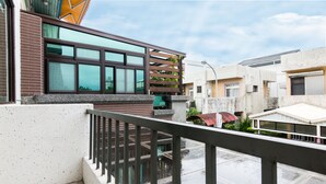 A residential building with a balcony, a window with a wooden slat design, and a street view.