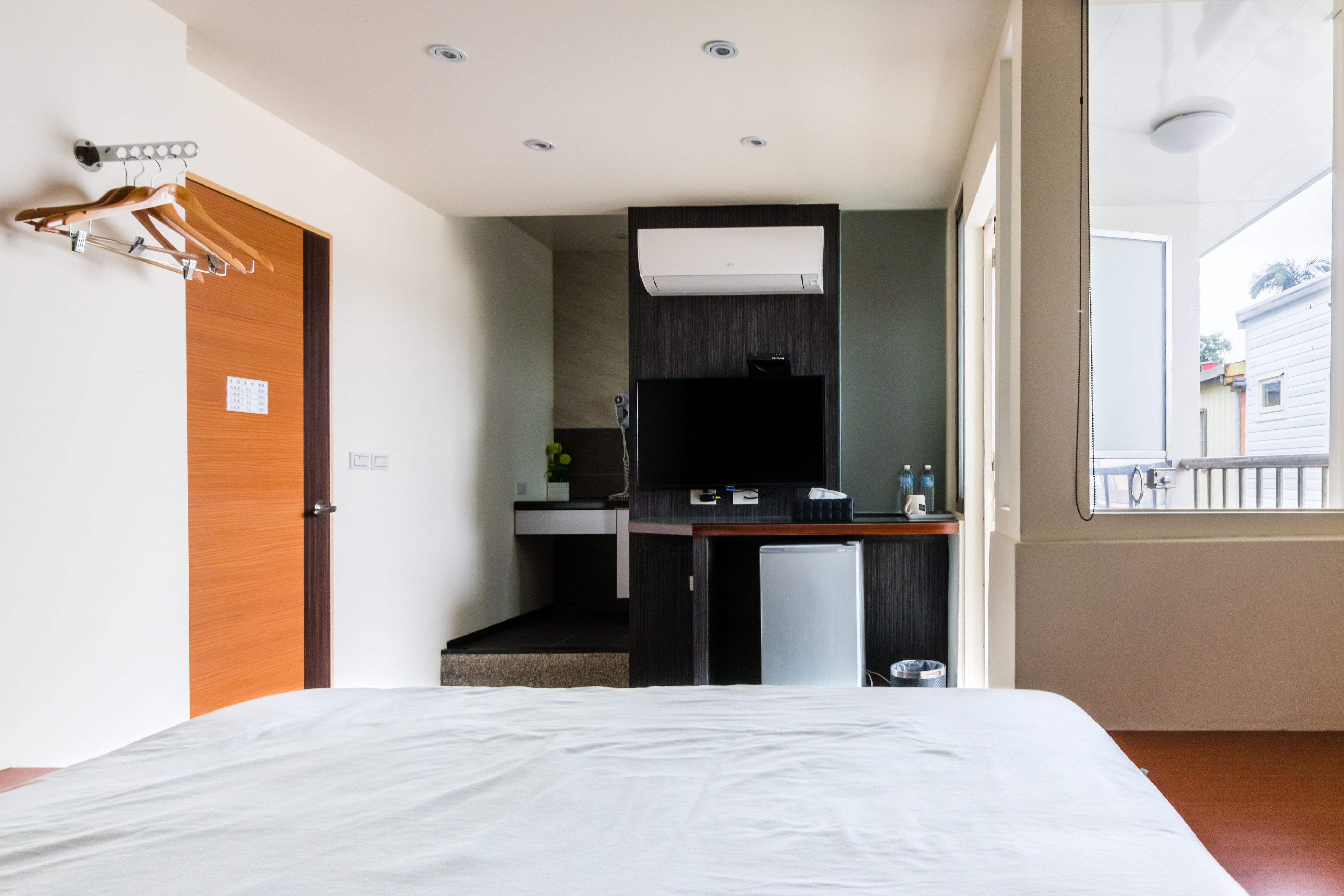 A hotel room with a bed, a kitchenette, and a window with a view of the outside.