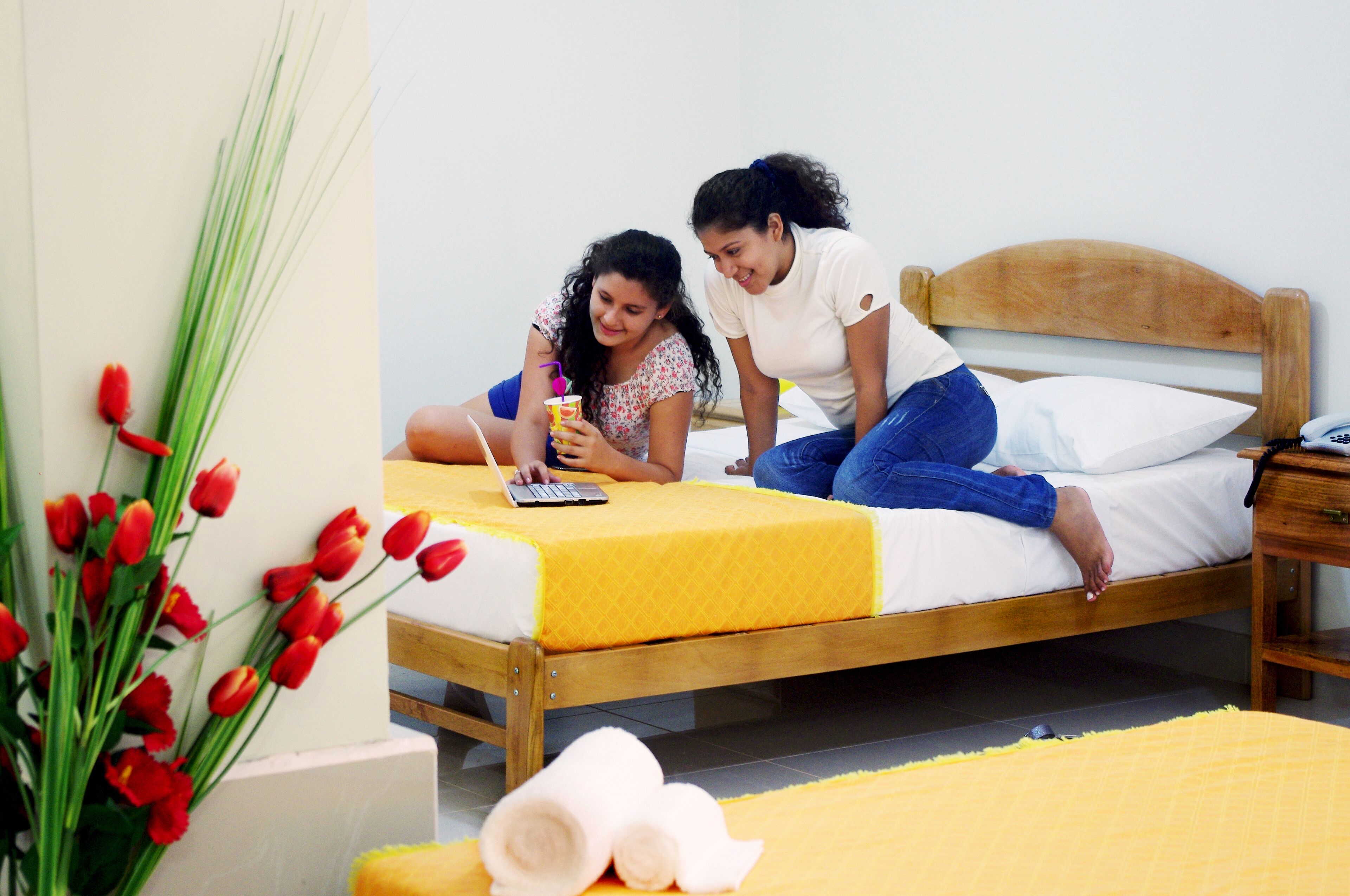 A bed with a yellow bedspread, a wooden headboard, and a bedside table with a phone.