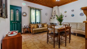 Una habitación acogedora con techo de madera, una puerta verde, un sofá, una mesa de comedor con sillas y una chimenea.