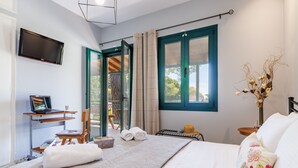 Habitación de hotel moderna con cama, escritorio, computadora portátil, televisor y vistas al exterior.