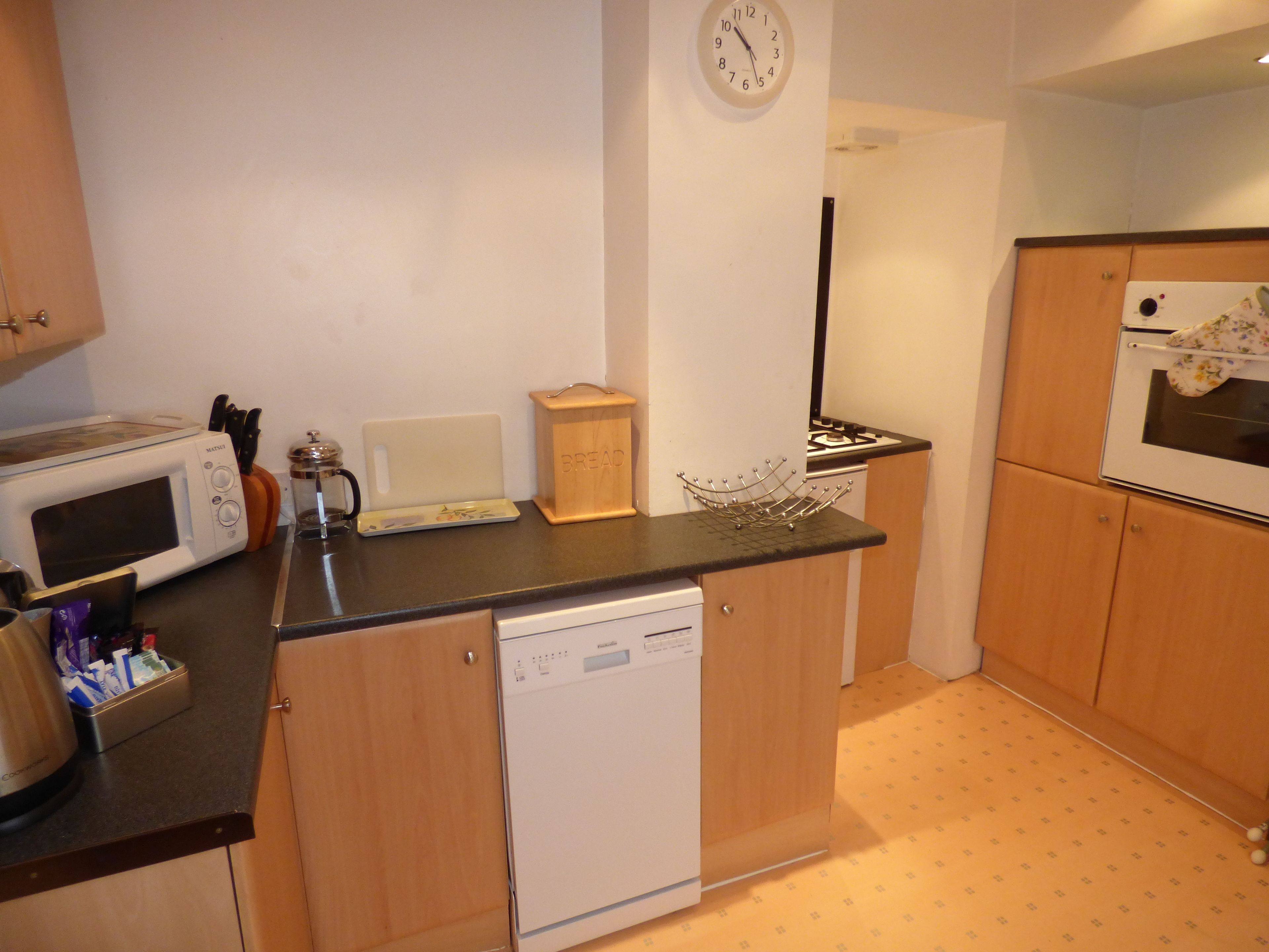 A compact kitchen with a microwave, toaster, and a bread box.