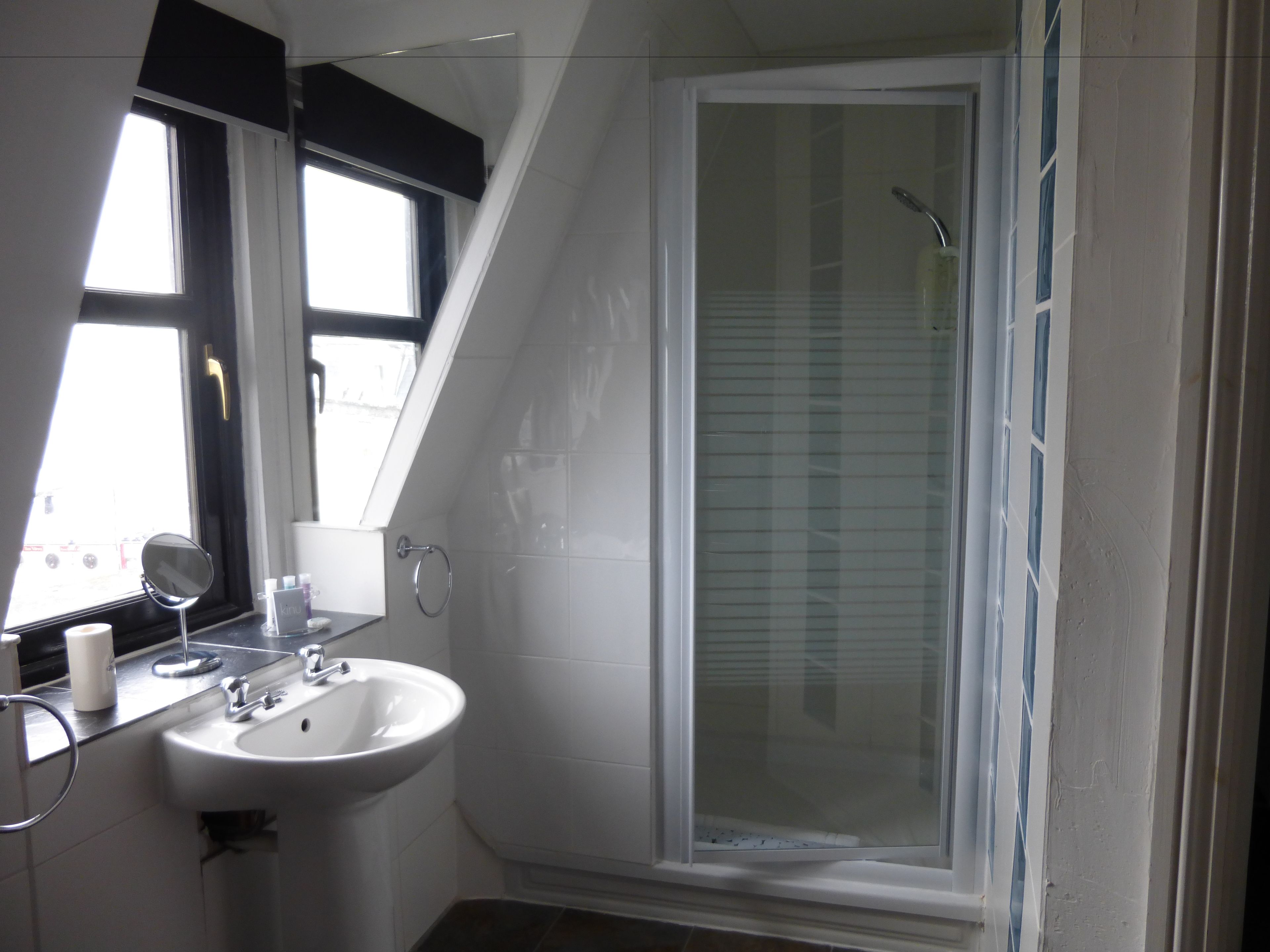 Un baño moderno con un lavabo blanco, espejo y ducha.