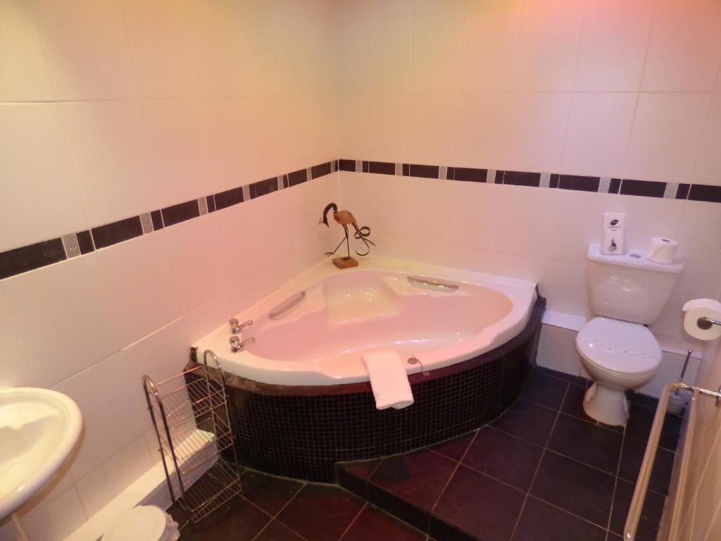 A bathroom with a large bathtub, a toilet, and a sink.