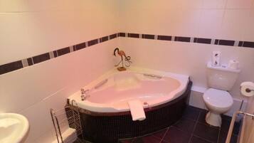 A bathroom with a large bathtub, a toilet, and a sink.
