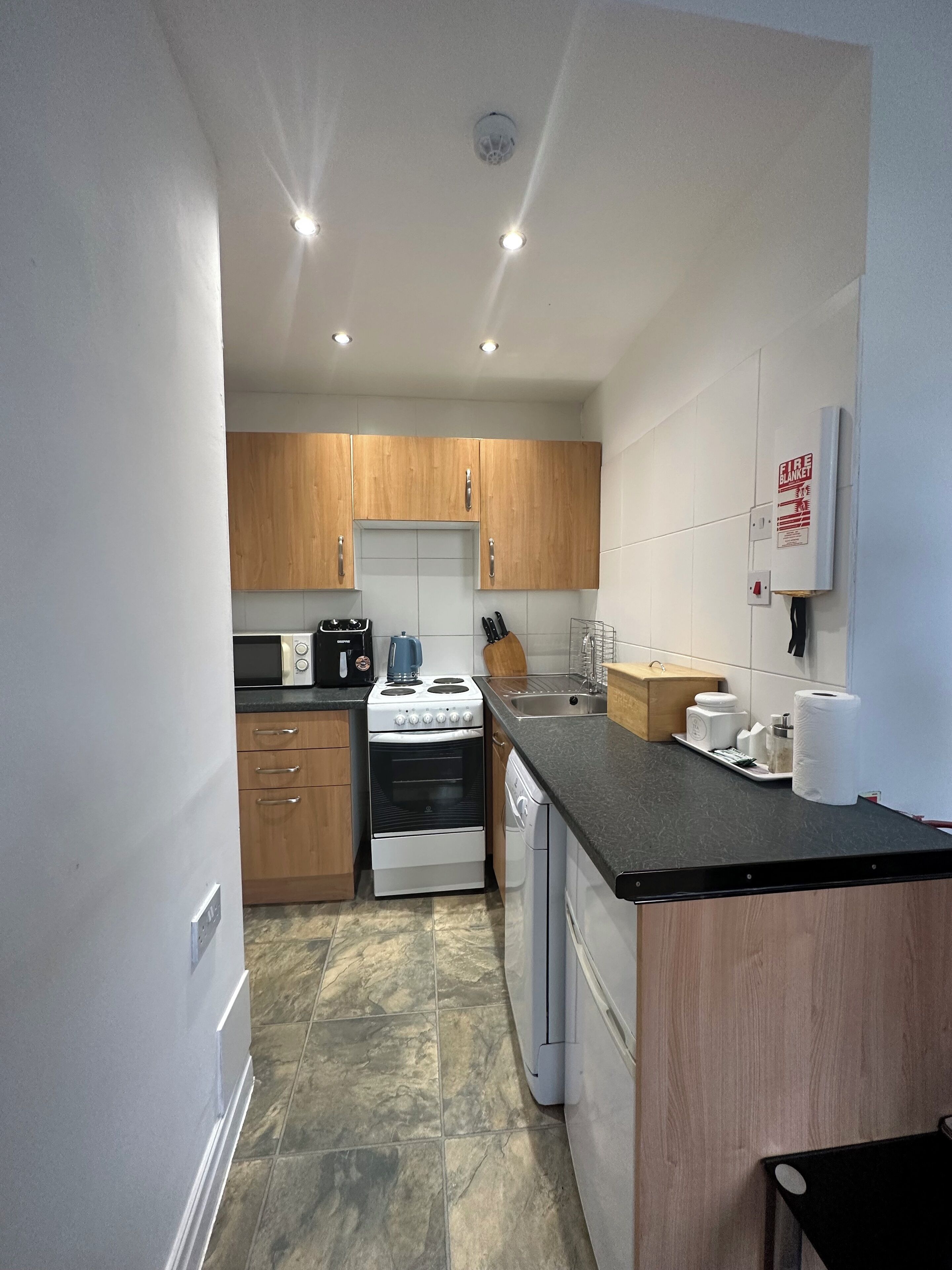 A compact kitchen with wooden cabinets, a stove, microwave, and a sink.