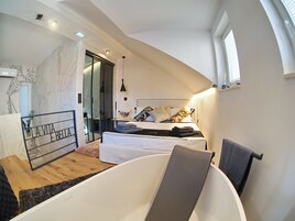 Quarto moderno com uma cama grande, uma banheira e uma porta de vidro que dá para uma varanda.