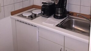 A compact kitchen with white cabinets, a stainless steel sink, a toaster, and a coffee maker. - Elbsandstein Apartment Altstadt (Erfurt)