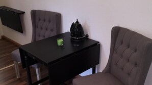 A small room with a black table, two grey chairs, a green candle, and a black kettle. - Elbsandstein Apartment Altstadt (Erfurt)