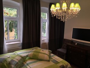 Une chambre à coucher avec un lit, une télévision, une commode et un lustre.