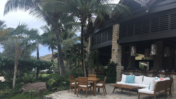 A patio with stone steps, wooden furniture, and a stone building with a black roof. - 2 Bedroom Bungalow-Style Villa (Basseterre)
