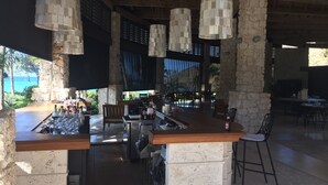 A bar area with a stone counter, hanging light fixtures, and a view of the ocean. - 2 Bedroom Bungalow-Style Villa (Basseterre)