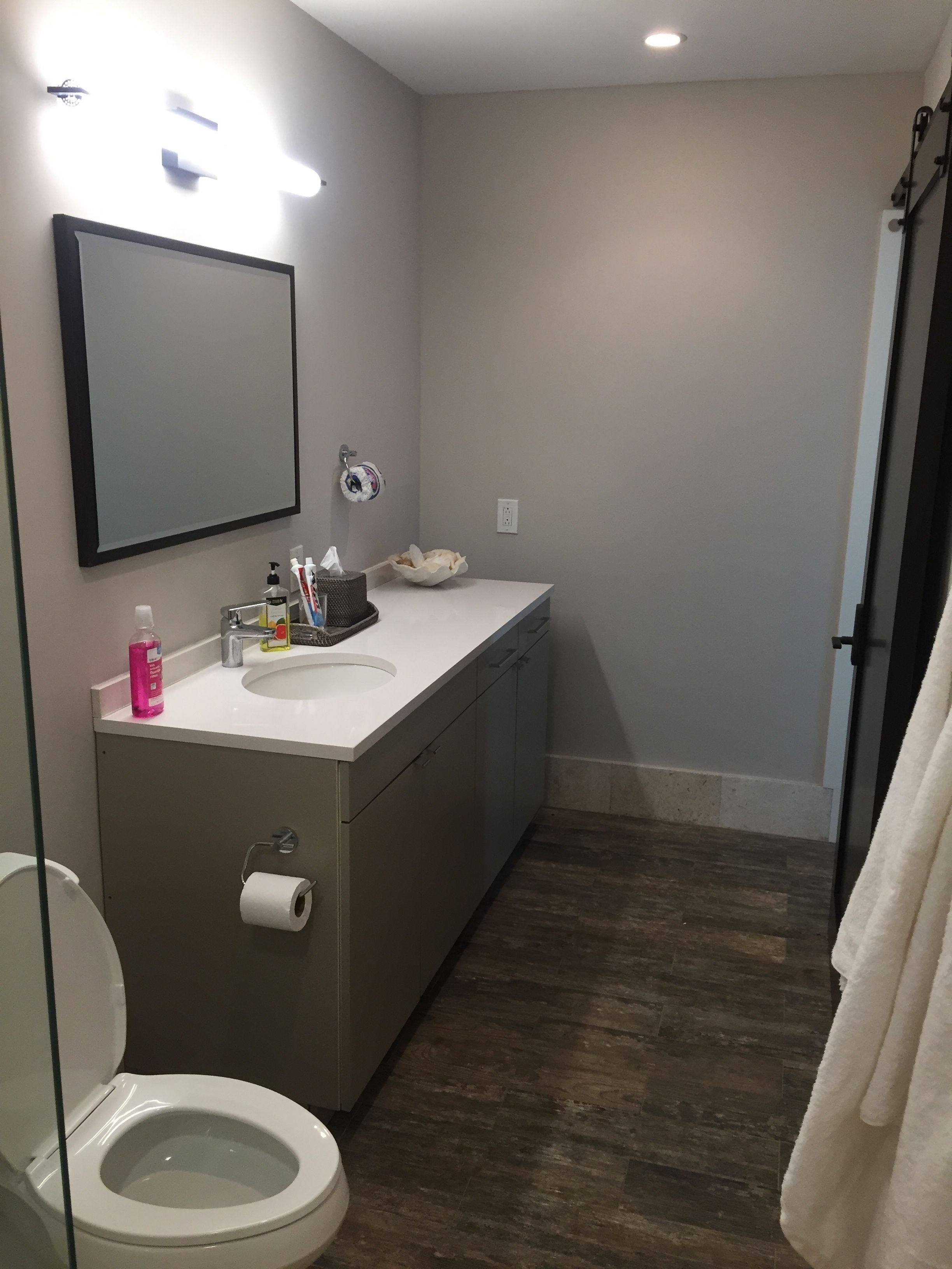 Un baño moderno con inodoro, lavamanos y espejo.