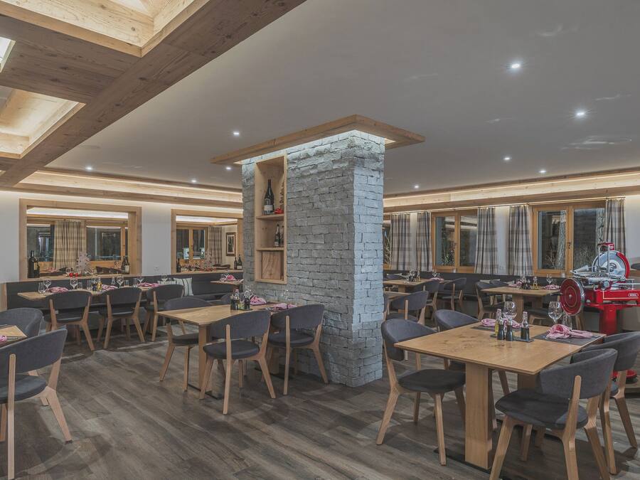 A restaurant with wooden tables and chairs, stone pillars, and a red food preparation station.