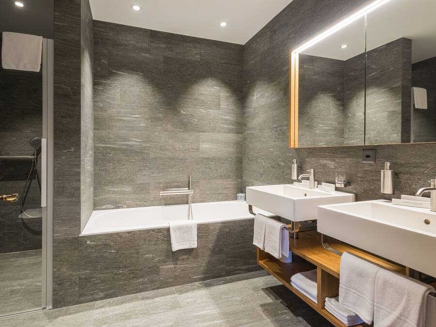 Un baño moderno con un espejo grande, dos lavamanos, una bañera y una ducha.
