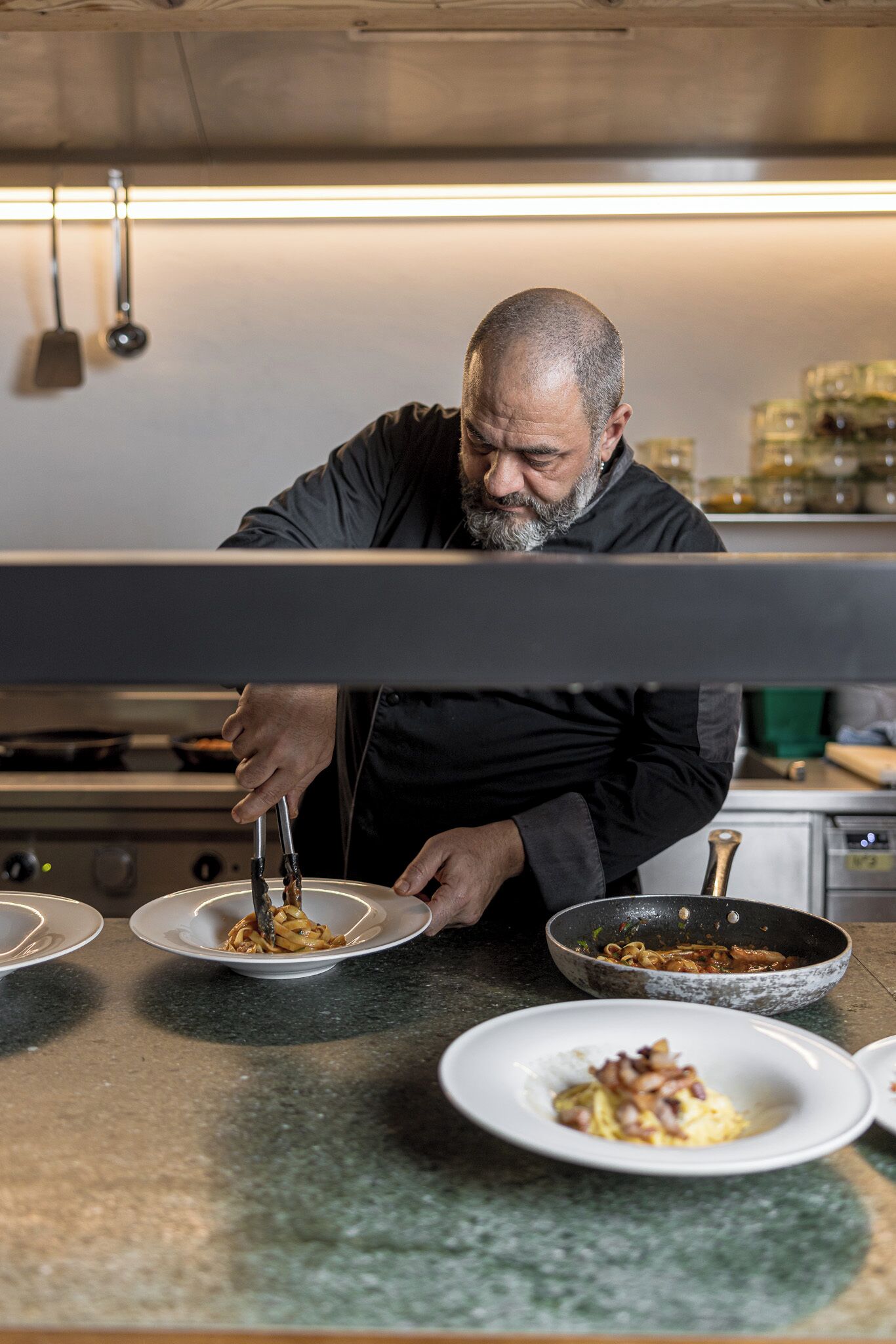 Un chef preparando comida en una cocina con electrodomésticos de acero inoxidable y una encimera de granito.