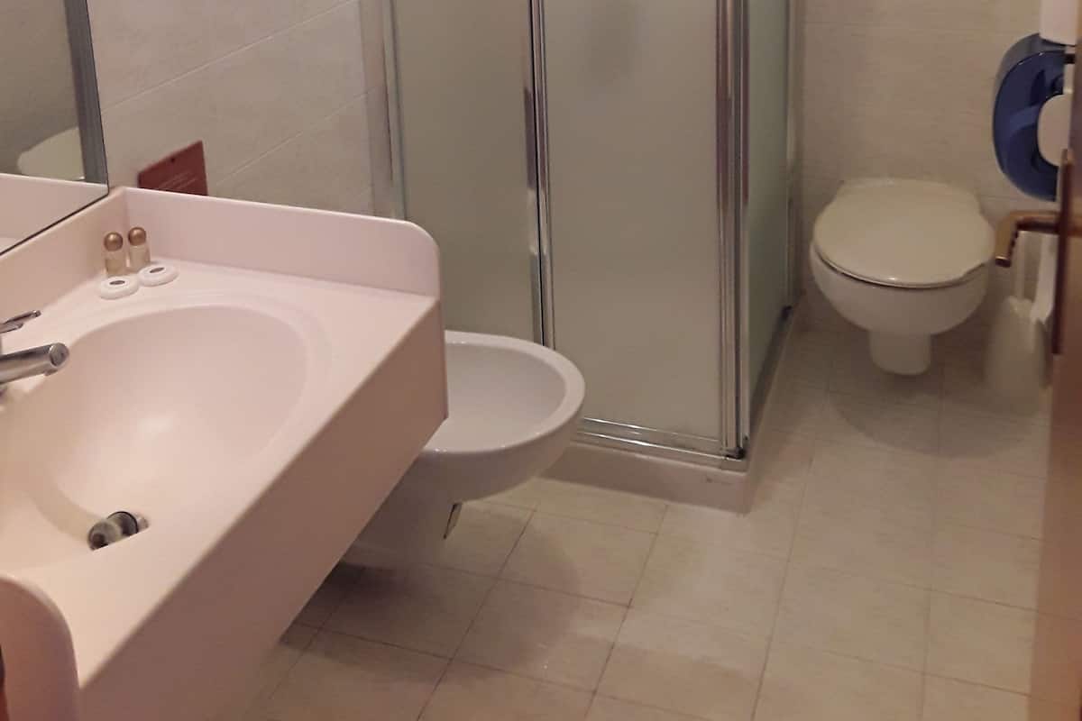 A bathroom with a glass-enclosed shower, a sink, and a toilet.