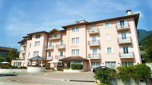 A multi-story hotel with balconies, a covered outdoor seating area, and a sign indicating it is a hotel. - Hotel Bellaria (Levico Terme)