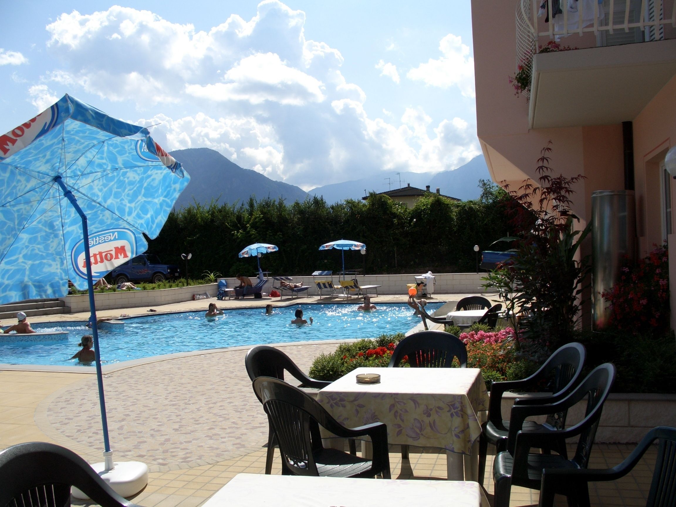 A pool area with umbrellas, lounge chairs, and a table with chairs.