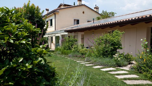 Una casa con un vialetto fiorito che conduce a un portico coperto.
