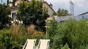 Un giardino con una vasca idromassaggio, due poltrone relax e una casa sullo sfondo.