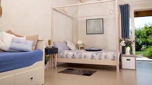 Una camera da letto con un letto, comodini, tende e vista su del verde all'esterno.