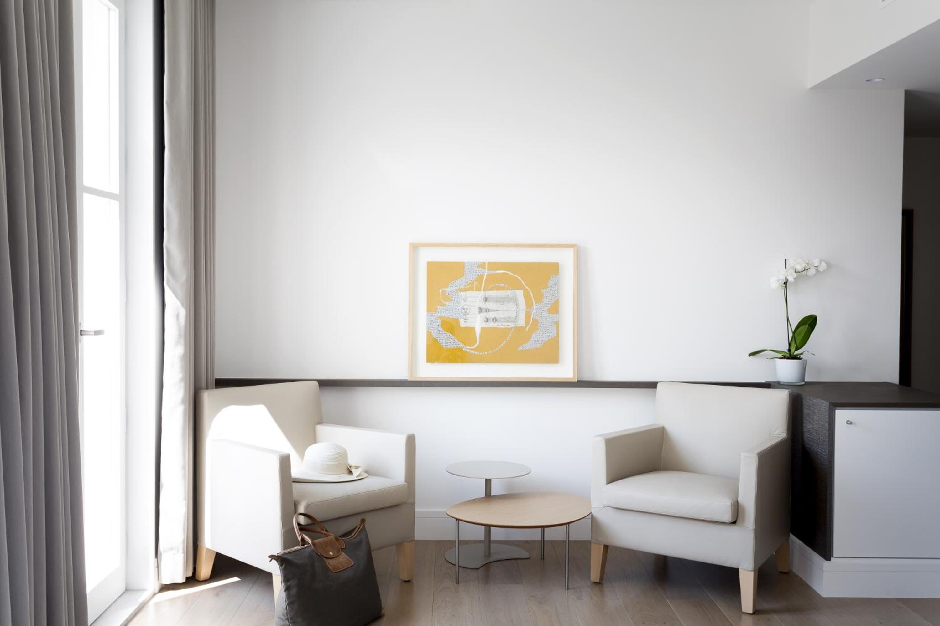 A modern living room with a sofa, a small round table, and a minimalist artwork on the wall.