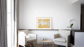 A modern living room with a sofa, a small round table, and a minimalist artwork on the wall.