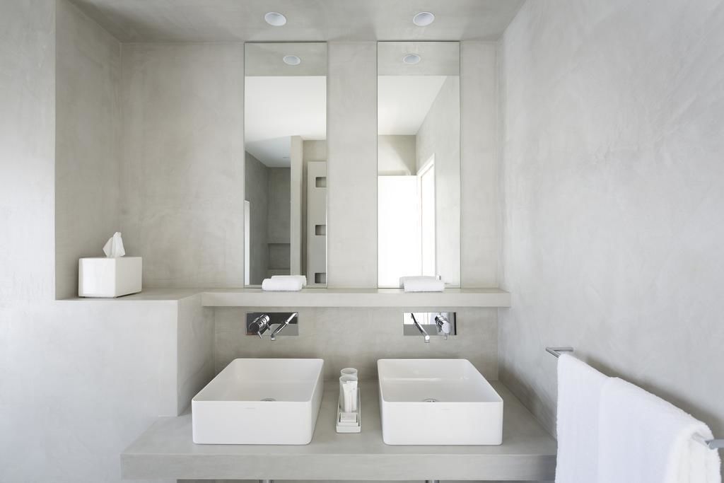 A modern bathroom with two white sinks, a large mirror, and a towel rack.
