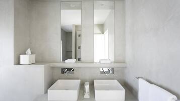 A modern bathroom with two white sinks, a large mirror, and a towel rack.