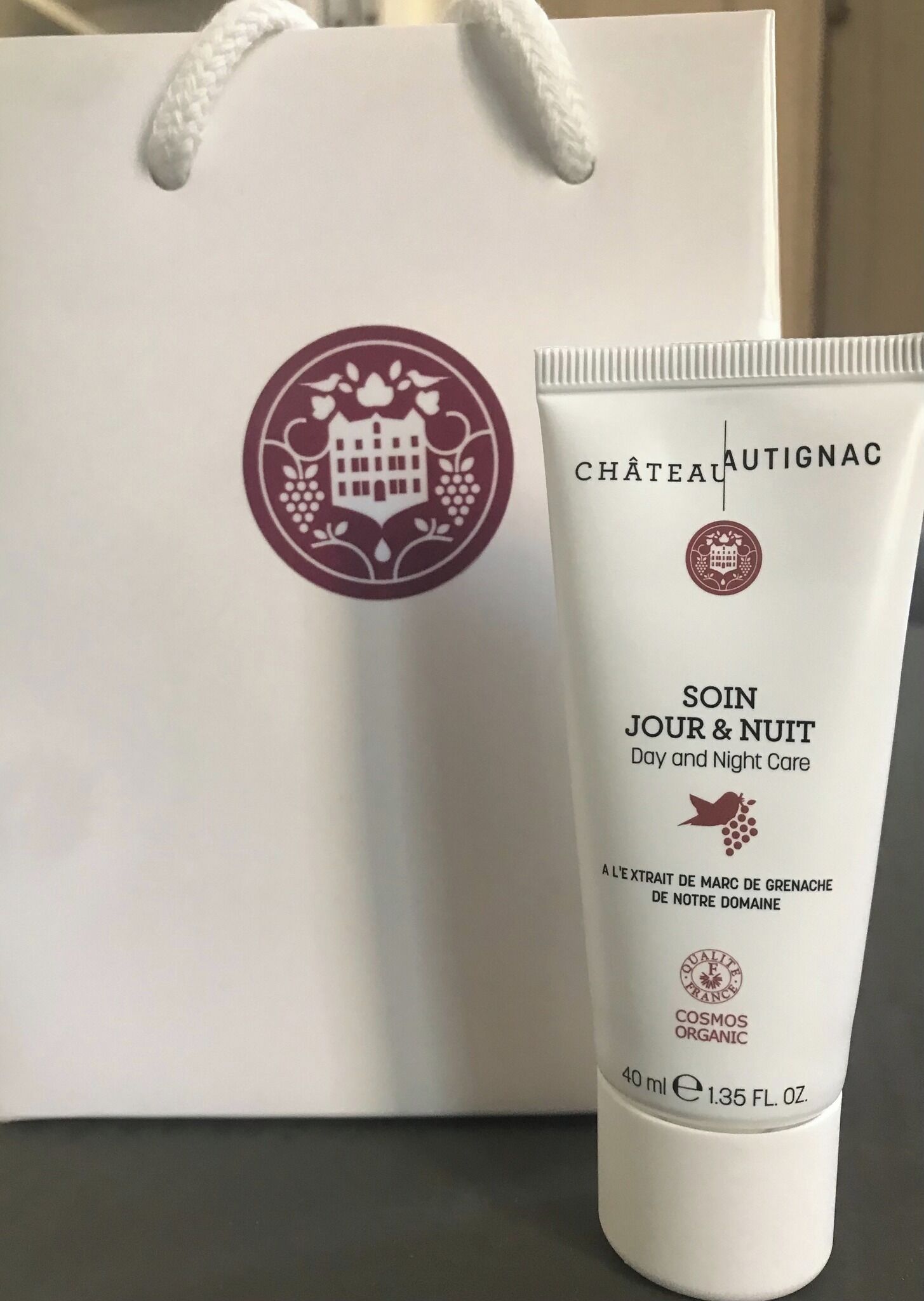 A skincare product tube and a white shopping bag with a logo.