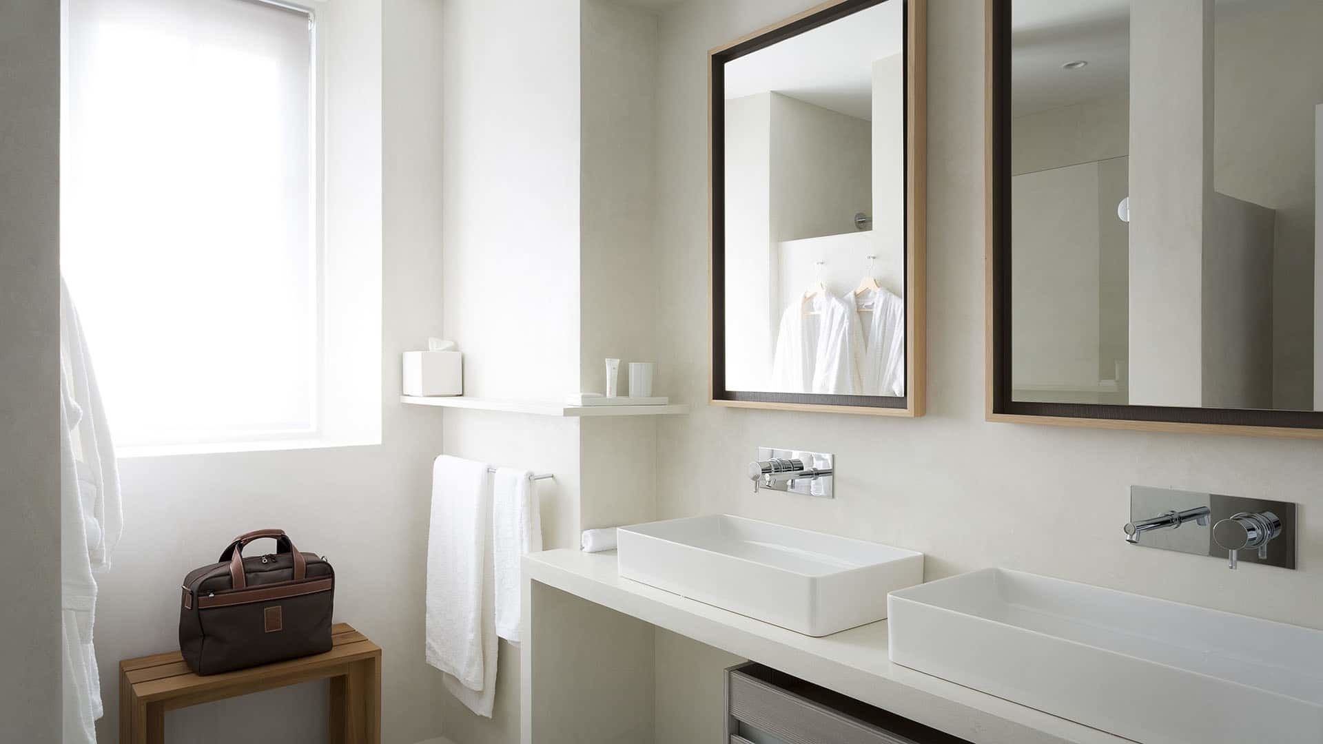 Een moderne badkamer met een grote spiegel, twee wasbakken en een handdoekrek.