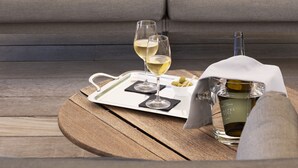 A modern living room with a grey sofa, a wooden coffee table, a tray with a bottle of wine, glasses, and olives. - Château Autignac (Autignac)