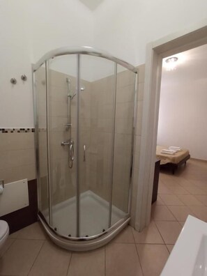 A glass-enclosed shower stall with a curved design, a toilet, and a small table with a towel. - Bed & Breakfast Villa Corallo (Porto Cesareo)
