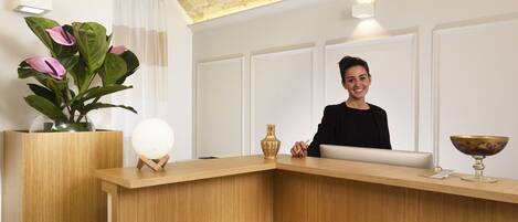 A reception desk with a vase of flowers, a spherical ornament, and a decorative bowl.
