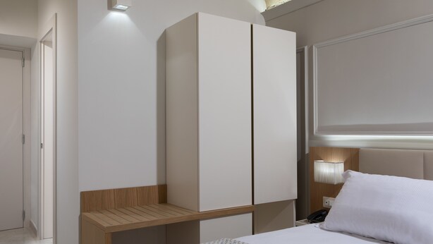 A modern hotel room with a bed, a wooden nightstand, a wardrobe, and a bedside lamp. - Magica Luna Boutique Hotel Roma (Rome)