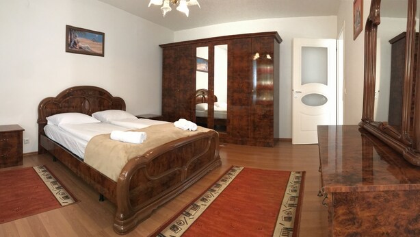 Une chambre à coucher avec un lit en bois, une armoire, une table de chevet et un miroir.