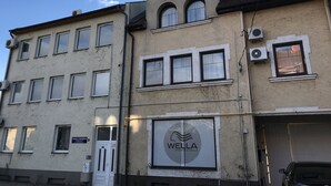 Un immeuble à plusieurs étages, avec une enseigne indiquant « WELLA PROFESSIONALS » au rez-de-chaussée.